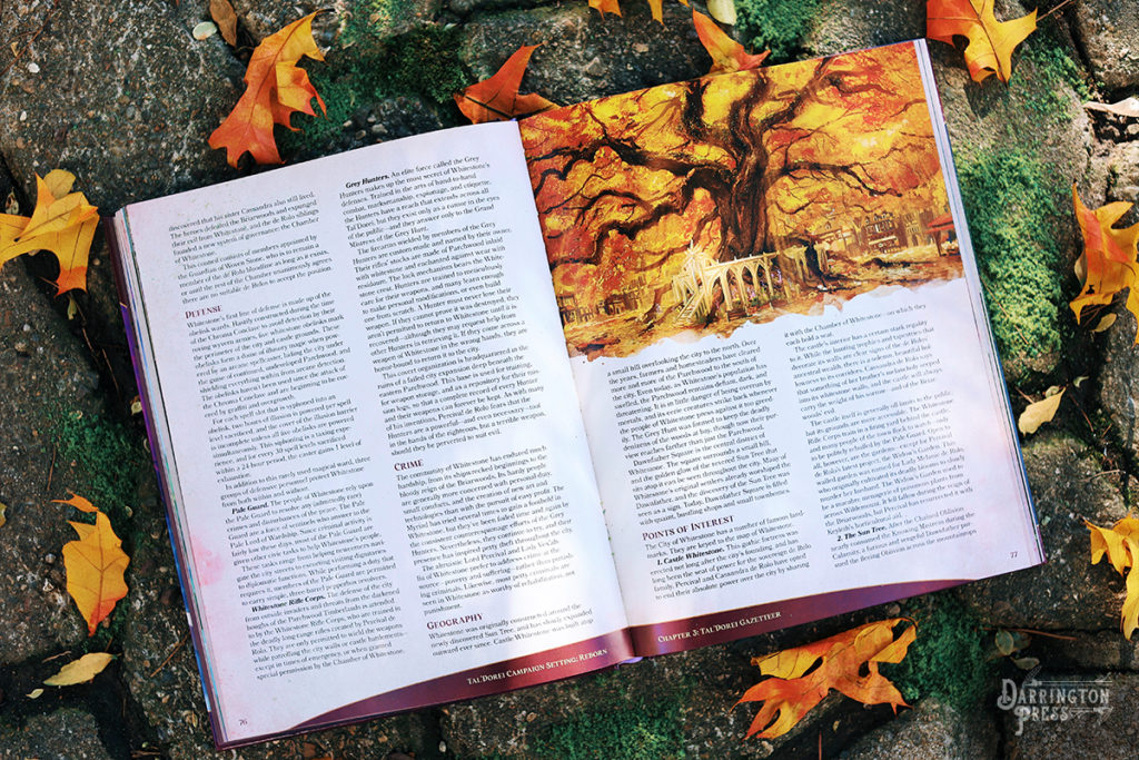 Tal'Dorei Campaign Setting Reborn, depicting the Sun Tree of Whitestone, illustrated by Kent Davis and photographed by Captain Dangerous. Illustration alt-text: A gigantic tree in the centre of a city, its trunk and branches thick and twisting, its leaves amber, red, and glowing with divine sunlight. The trunk of the tree is surrounded by a stone column platform and a staircase leading up to the tree. A sun with a face made of stone is carved above the staircase. 